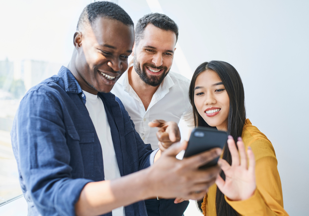 3 friends looking at a mobile phone smiling